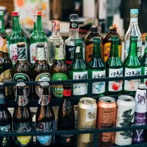 A vibrant display of various alcohol bottles and cans on a rack in a bar setting.